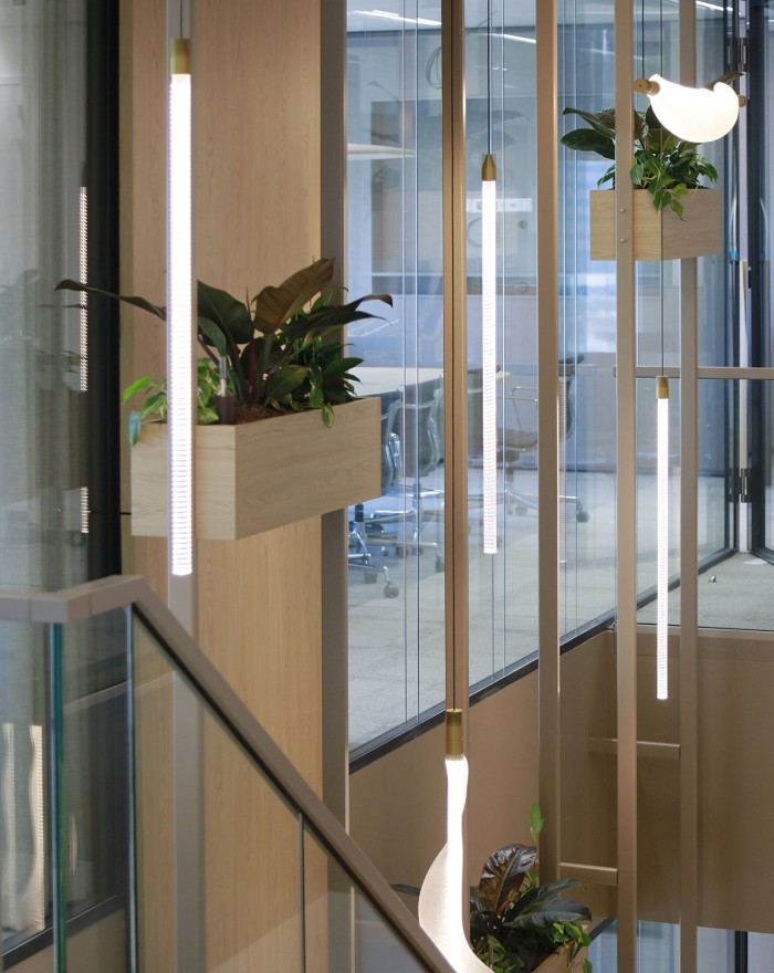 Modern kantoorinterieur met glazen wanden, houten panelen, hanglampen en planten