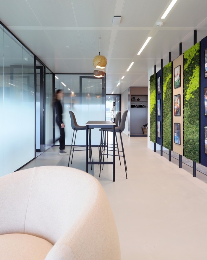 Moderne kantoorruimte met hoge tafel, glazen wanden en groene wanddecoratie