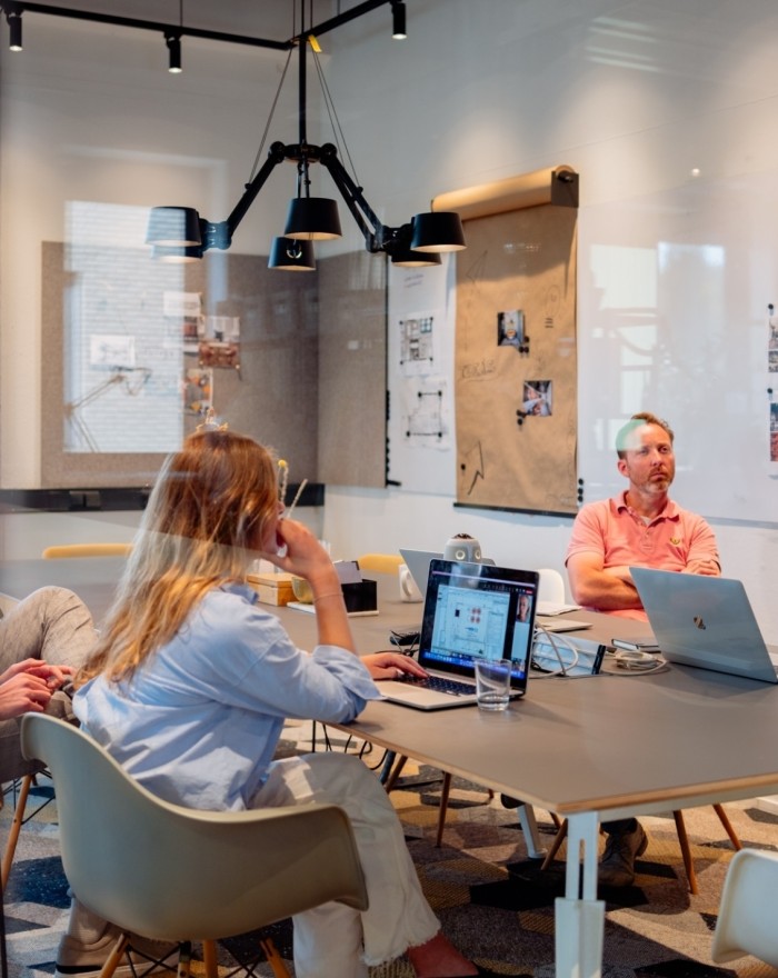 Teamvergadering in een moderne kantoorruimte met laptops en presentatiebord