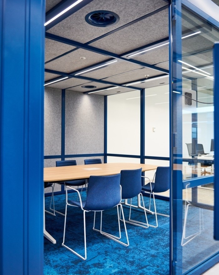 Moderne vergaderruimte met blauwe stoelen, houten tafel en glazen wanden in een kantooromgeving