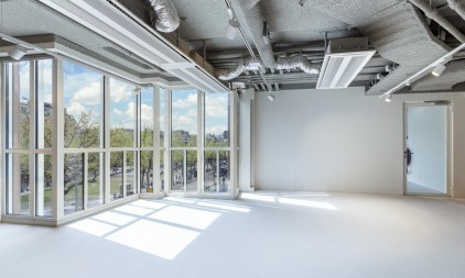 Bright office space with large windows and natural daylight overlooking trees and buildings
