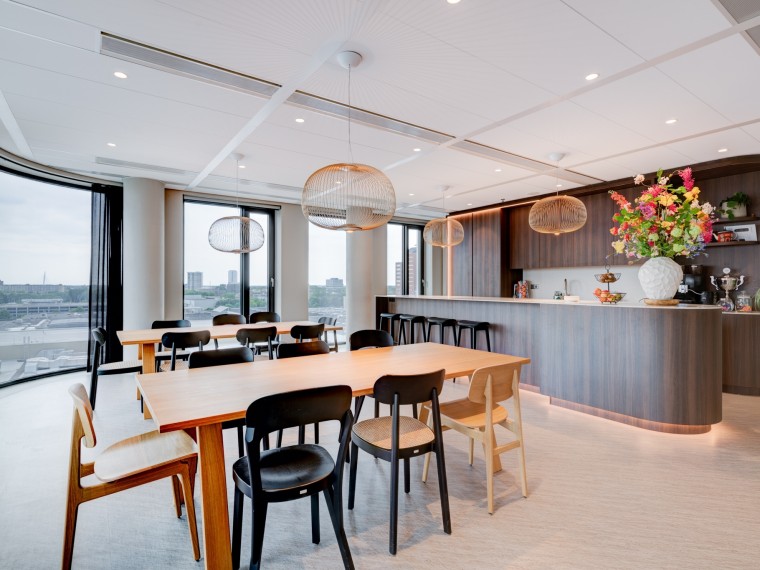 Modern pantry and meeting space with wooden furniture, pendant lighting and large windows overlooking the city of Utrecht.