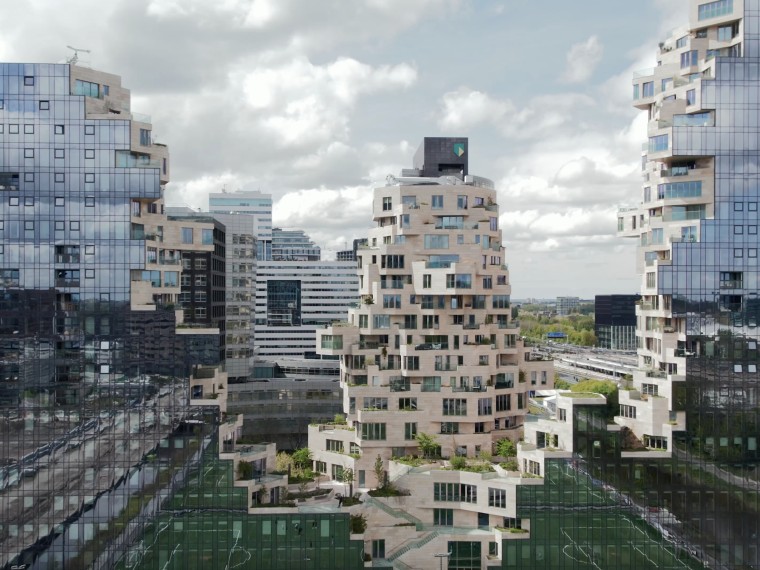 Luchtfoto van het Valley-complex in Amsterdam, met de kenmerkende terrassen, groene daken en moderne glasgevels.