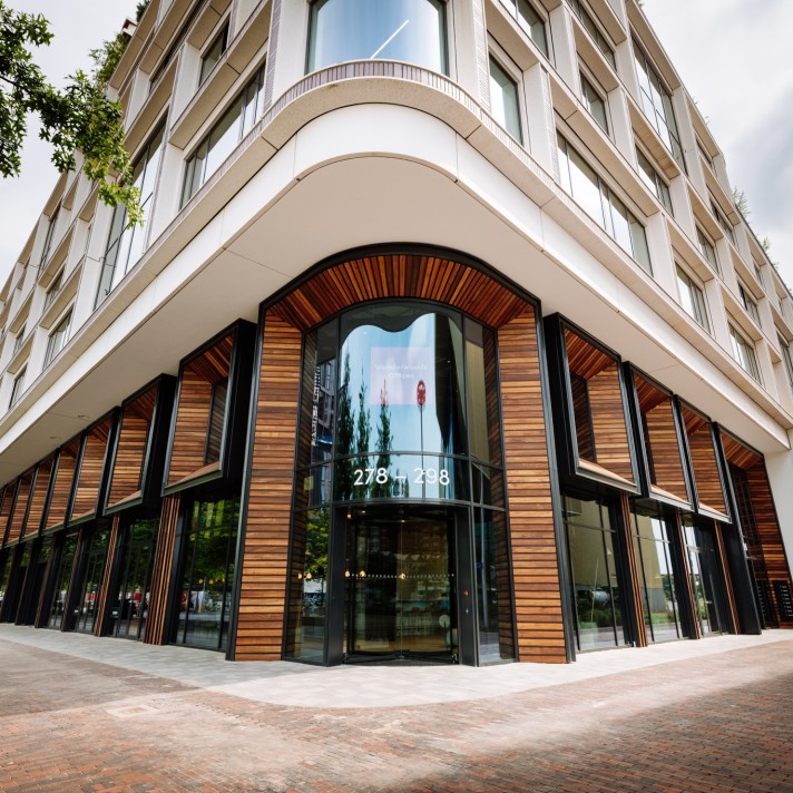 Moderne gevel van het Wonderwoods-gebouw in Utrecht met houten lamellen, grote glaspartijen en een opvallende ronde entree.