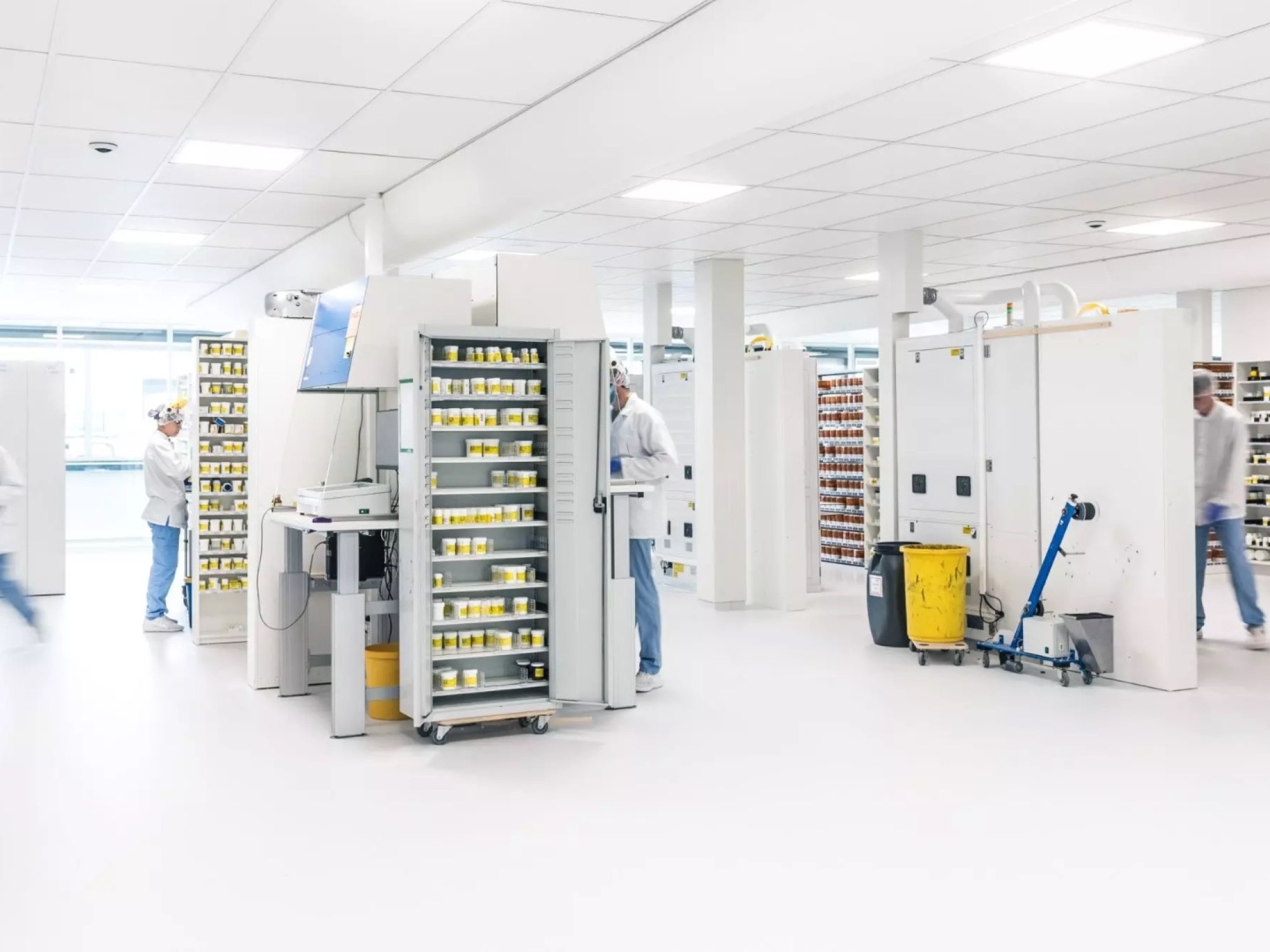 Cleanroom productieruimte met gele en groene kratten en medewerkers in beschermende kleding.