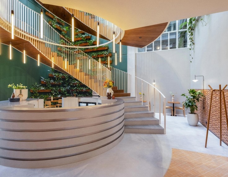 Moderne kantoorentree met ronde receptiebalie en houten trap met groene wandbeplanting.