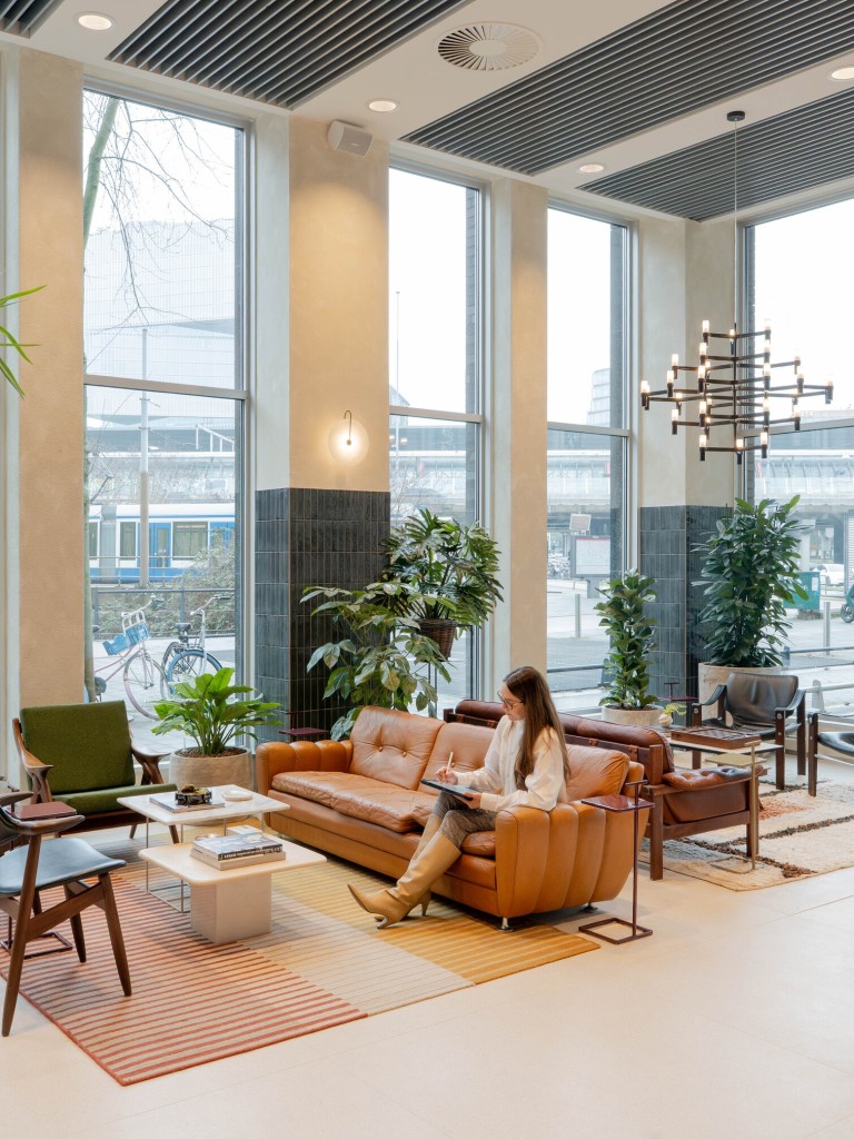 Moderne kantoor lobby met zitgedeelte, grote ramen en veel planten