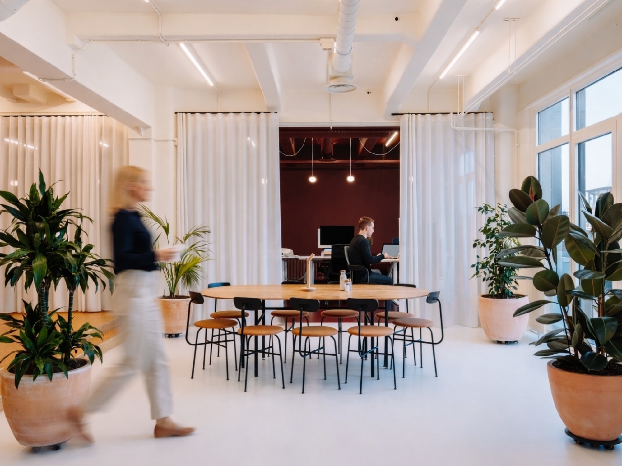 Gezamenlijke coworking ruimte met grote tafel, veel planten en informele werkplekken