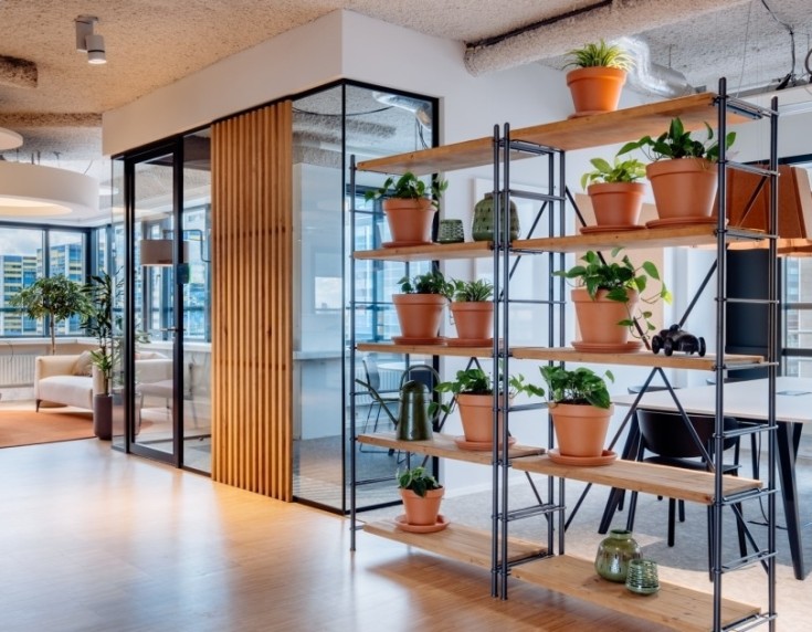 Moderne vergaderruimte met oranje bureaustoelen, houten tafel en groot presentatiescherm aan de muur.