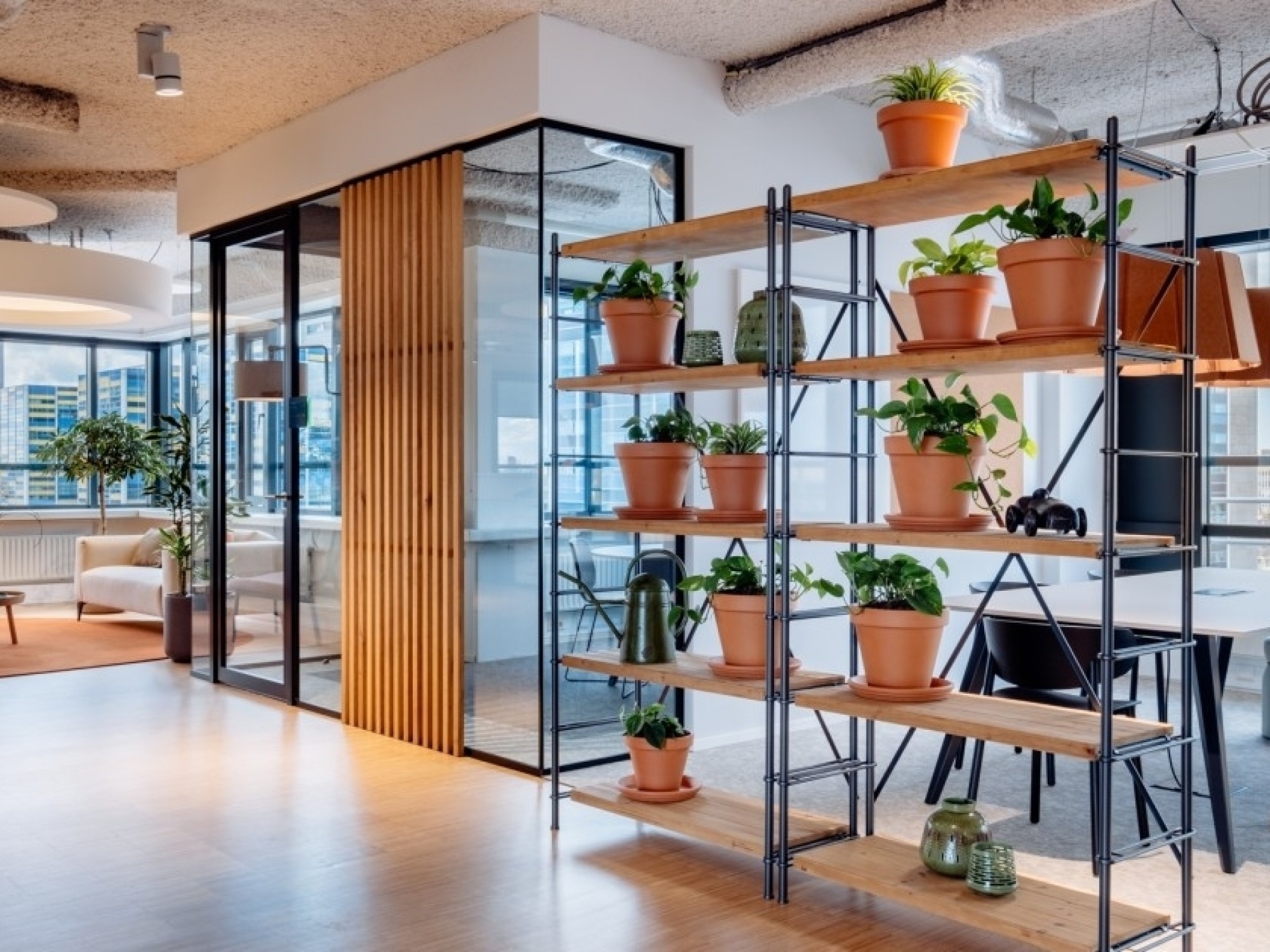 Moderne vergaderruimte met oranje bureaustoelen, houten tafel en groot presentatiescherm aan de muur.