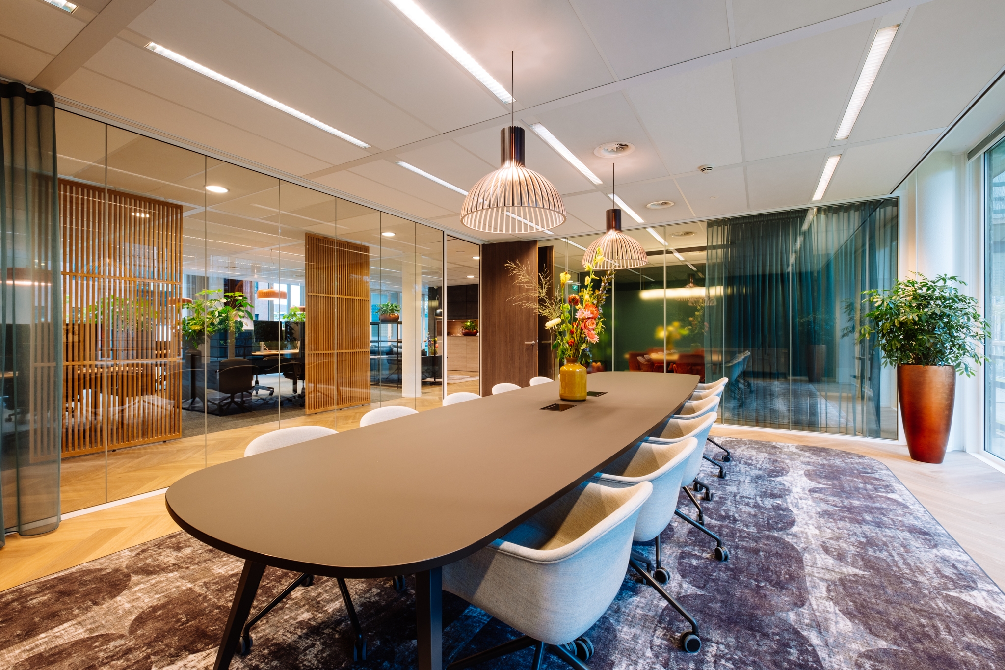 Grote vergaderruimte bij Bloei Vermogen met lange tafel, comfortabele stoelen, warme verlichting en glazen wanden.