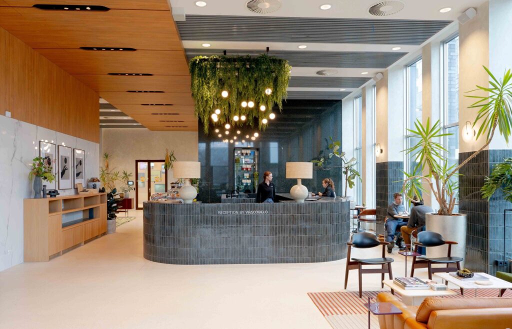 Moderne, groene receptieruimte met planten en helverlichte ontvangstbalie.