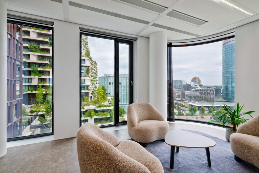 Moderne loungehoek met comfortabele stoelen en grote ramen met uitzicht op de stad.