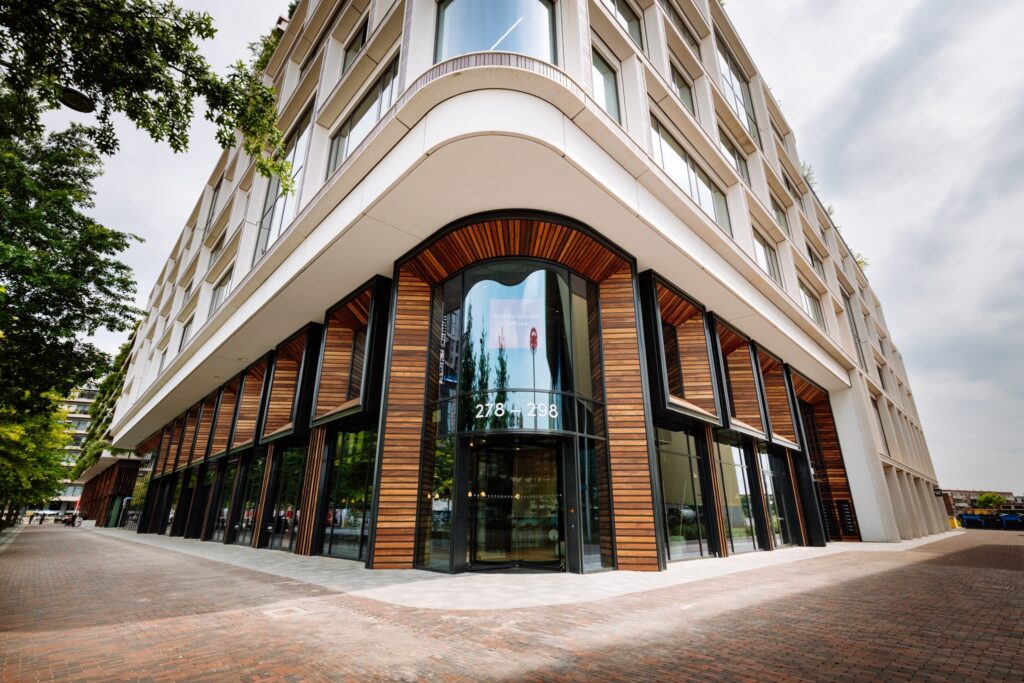 Moderne gevel van het Wonderwoods-gebouw in Utrecht met houten lamellen, grote glaspartijen en een opvallende ronde entree.