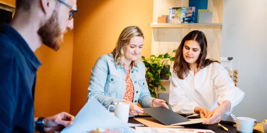 Twee vrouwen bespreken documenten tijdens overleg in moderne kantooromgeving.