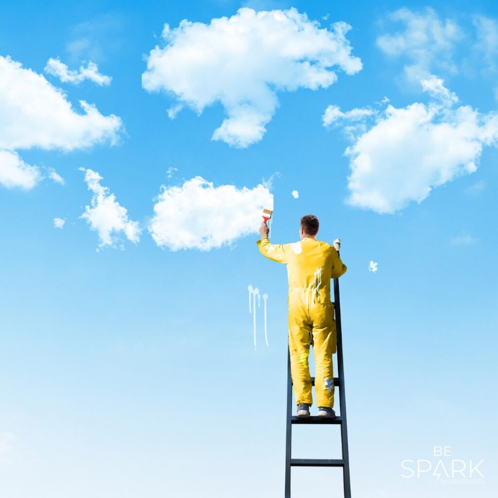 Persoon in gele outfit op een ladder die wolken schildert tegen een blauwe lucht.”