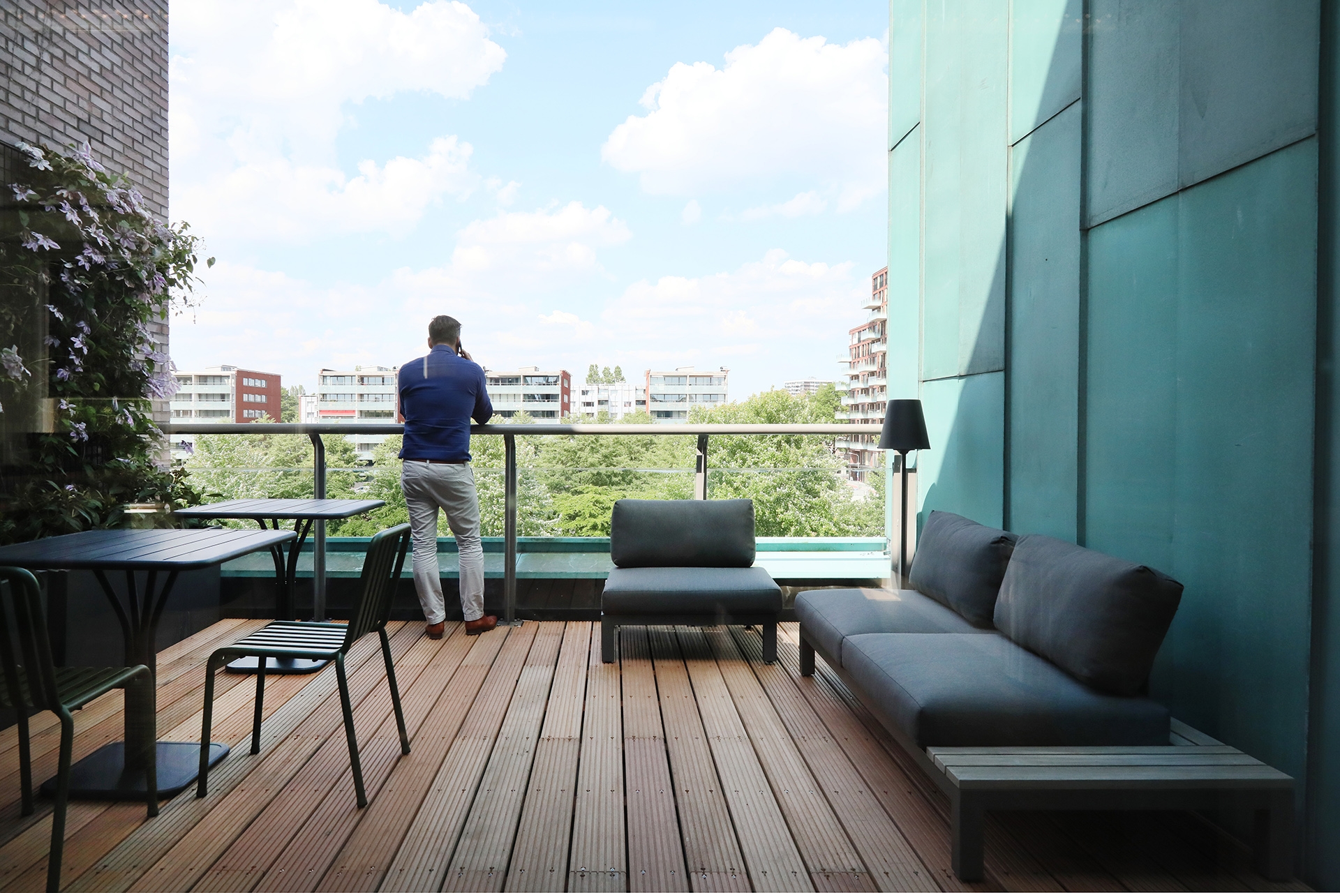 Kantoor dakterras met loungeset en uitzicht over de stad, een man staat bij de balustrade.
