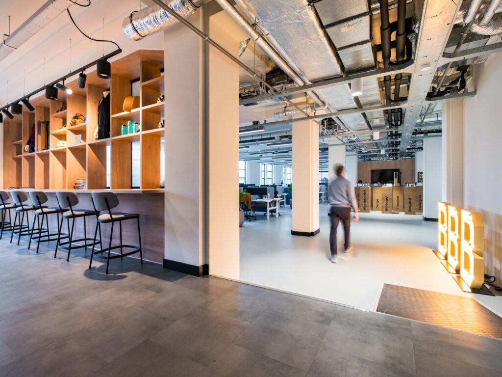 Moderne kantoorruimte met open werkplekken en een persoon die voorbijloopt.
