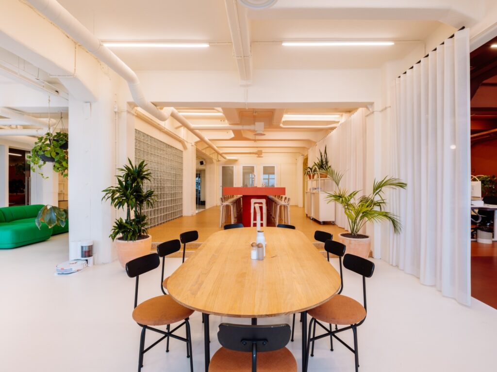 Een moderne kantoorruimte met een lange houten tafel en omgeven door planten.