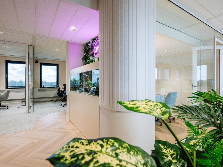 Een modern kantoor met glazen wanden, planten en een verlichte "open" neon sign aan de muur.