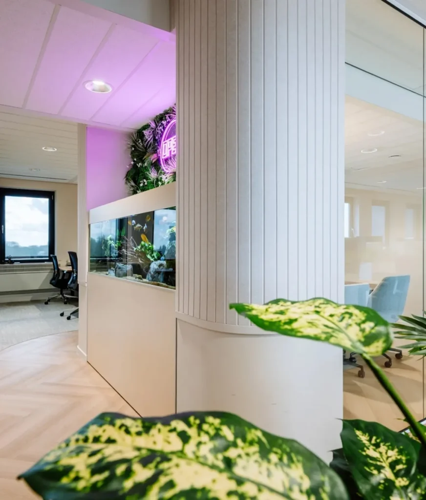 Moderne kantooromgeving met een aquarium, groene planten en paarse accentverlichting.