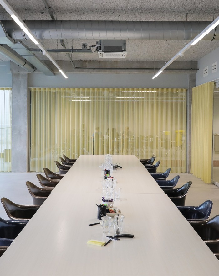 Een moderne vergaderruimte met een lange tafel en omringende stoelen, gelegen in een kantooromgeving.