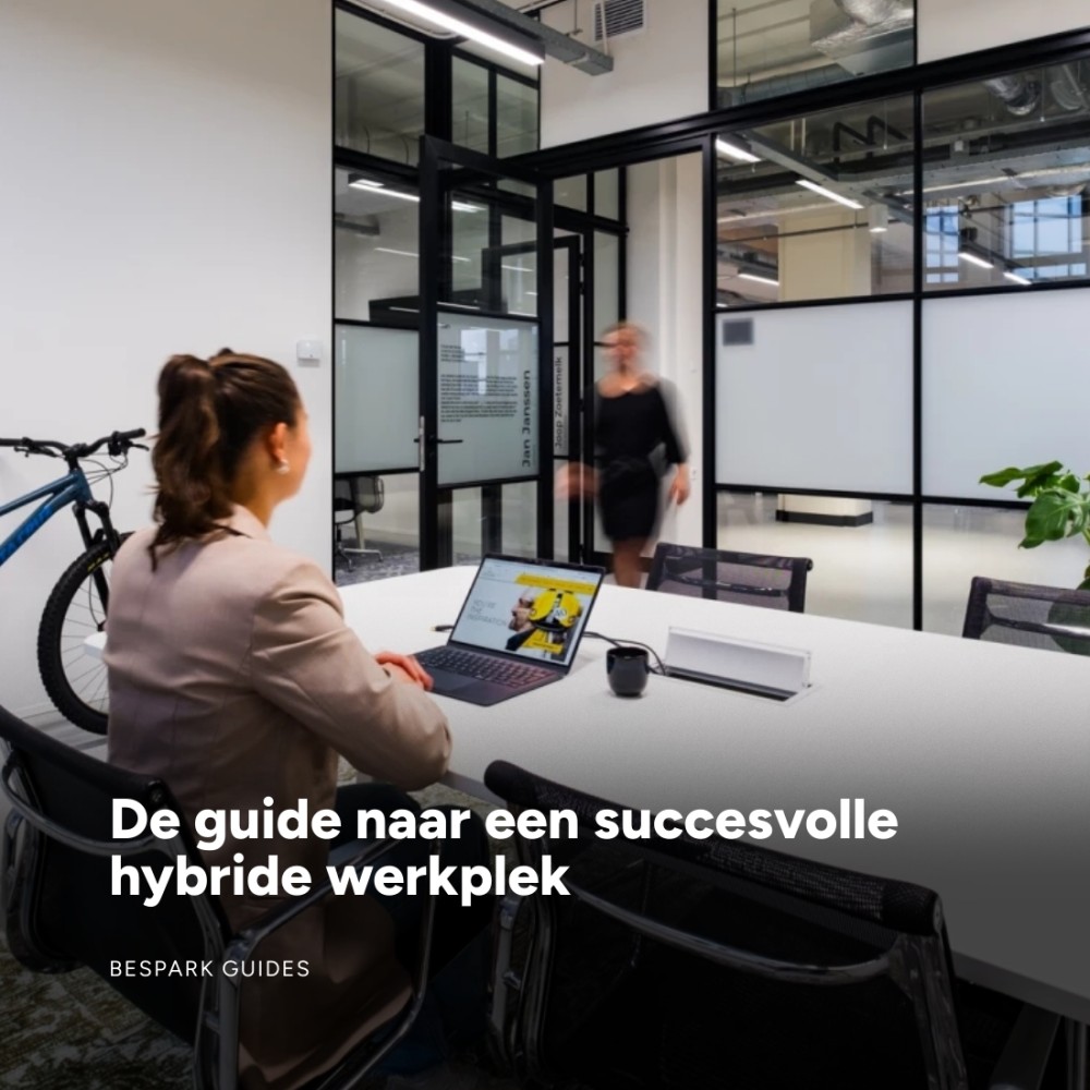 Een moderne hybride werkplek met een persoon achter een laptop en een binnenkomende collega.