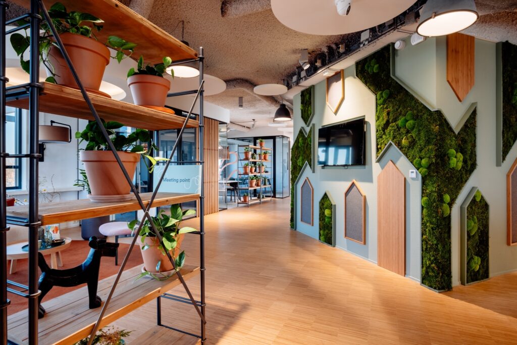 Modern kantoorinterieur met houten vloer, plantenrekken en een groene moswand.