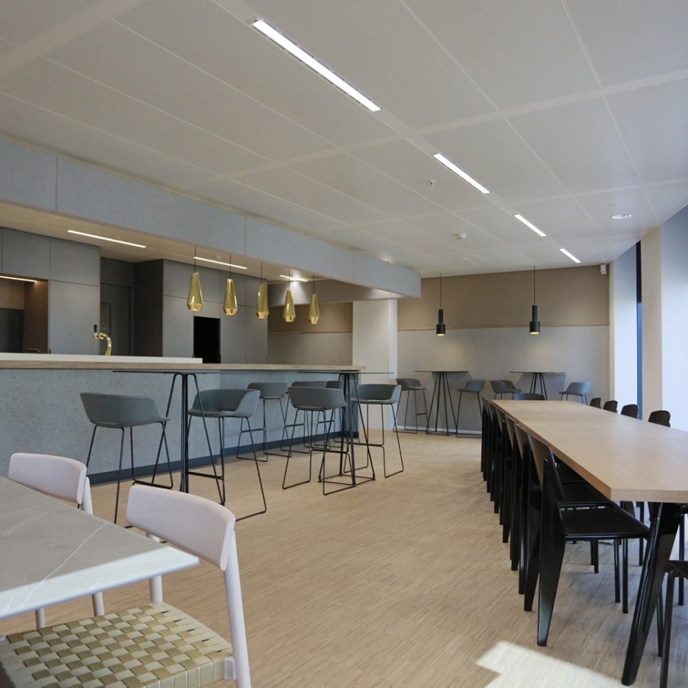 Moderne kantoorruimte met een lange tafel en hoog zitgedeelte aan een bar.