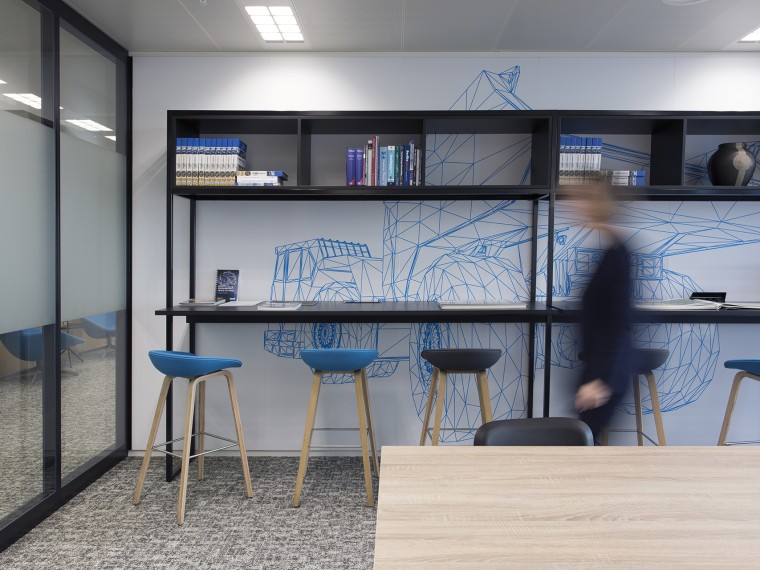Een moderne kantoorruimte met een geometrische muurtekening en hoge zitplaatsen.