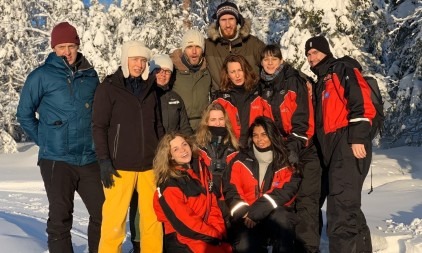 Een groep mensen gekleed in winterkleding poseert samen in de besneeuwde natuur van Lapland.