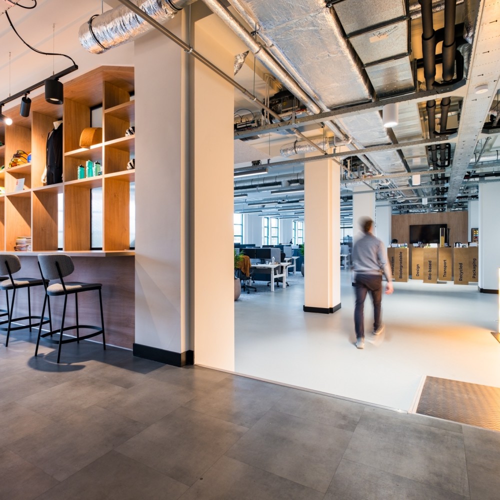 Industrieel kantoor met houten interieur en zichtbare leidingen, gericht op duurzame inrichting.