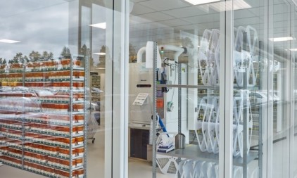 Een laboratorium met glazen wanden, met apparatuur en stellingkasten vol flessen.