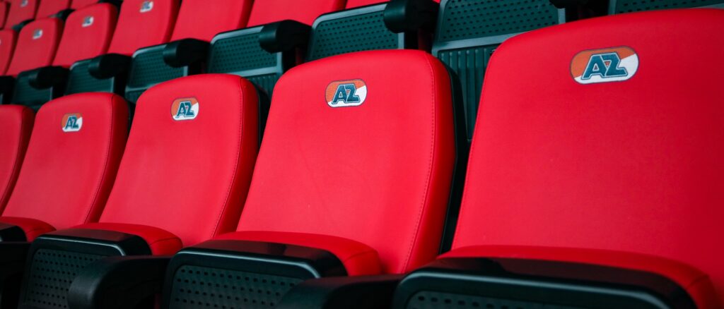 Rode stadionstoel met AZ-logo op de rugleuning.