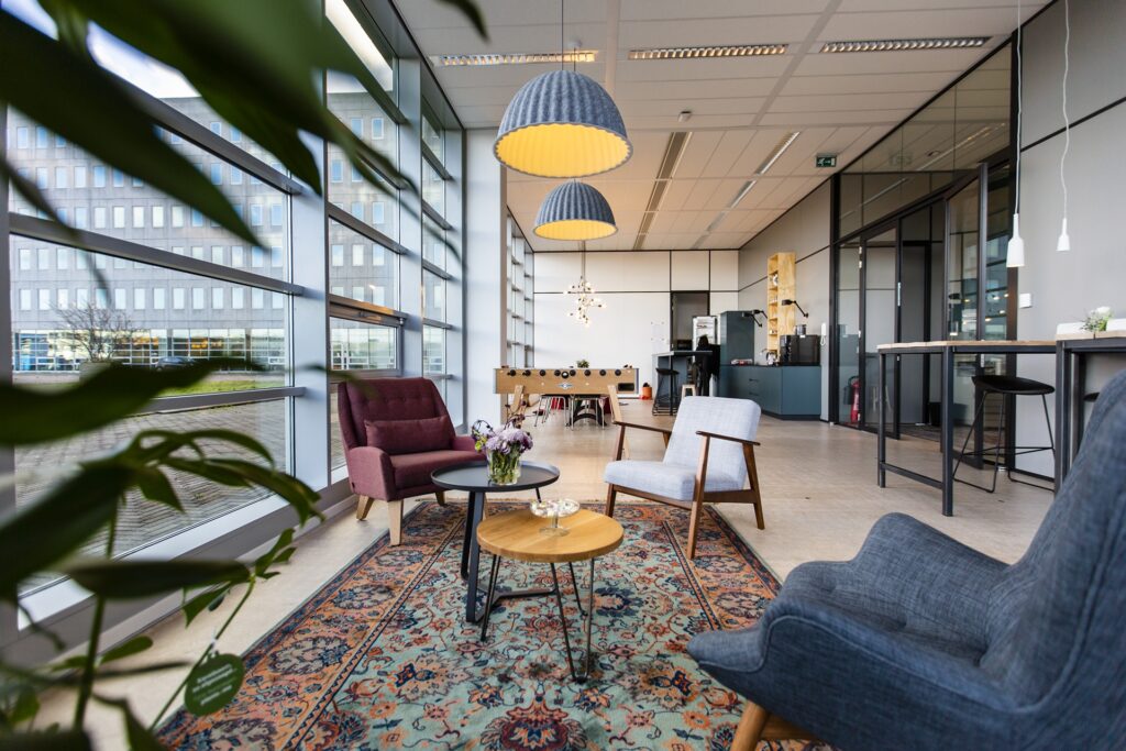 Huiskamerachtige zithoek in het Mare-kantoor in Amsterdam met fauteuils, vloerkleed en veel daglicht, ontworpen door BESPARK.