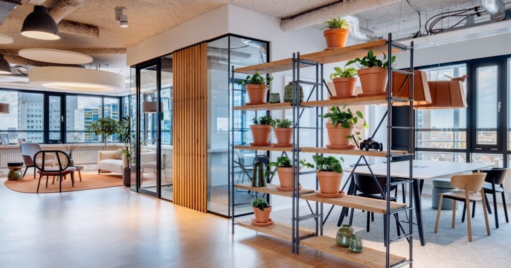 Moderne vergaderruimte met oranje bureaustoelen, houten tafel en groot presentatiescherm aan de muur.