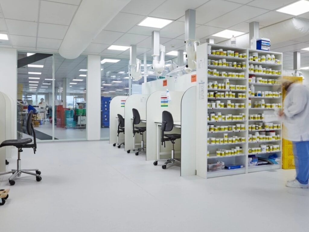 Een modern ingericht laboratorium met werkstations en een kast gevuld met potjes.