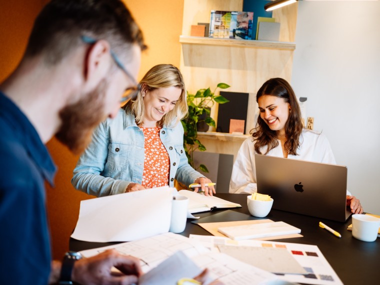Een groep collega's werkt samen aan een project aan een tafel in een moderne kantoorruimte.