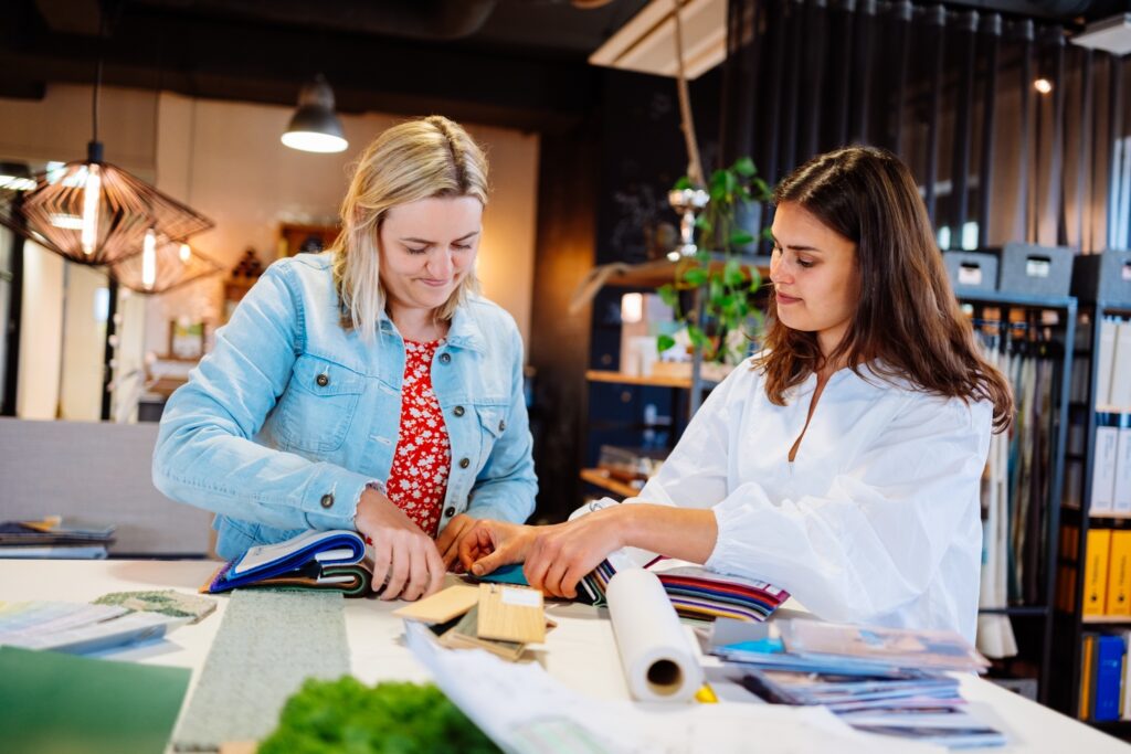 Two women are discussing colours and materials in a creative office environment.